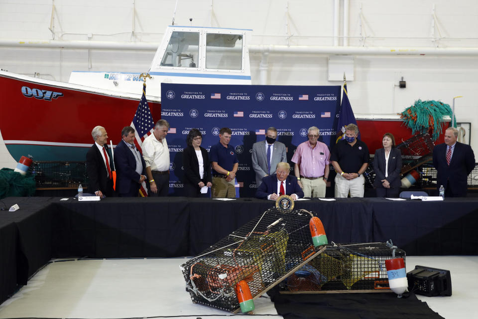 President Donald Trump signs an executive order on commercial fishing after speaking at a roundtable discussion with commercial fishermen at Bangor International Airport in Bangor, Maine, Friday, June 5, 2020. (AP Photo/Patrick Semansky)