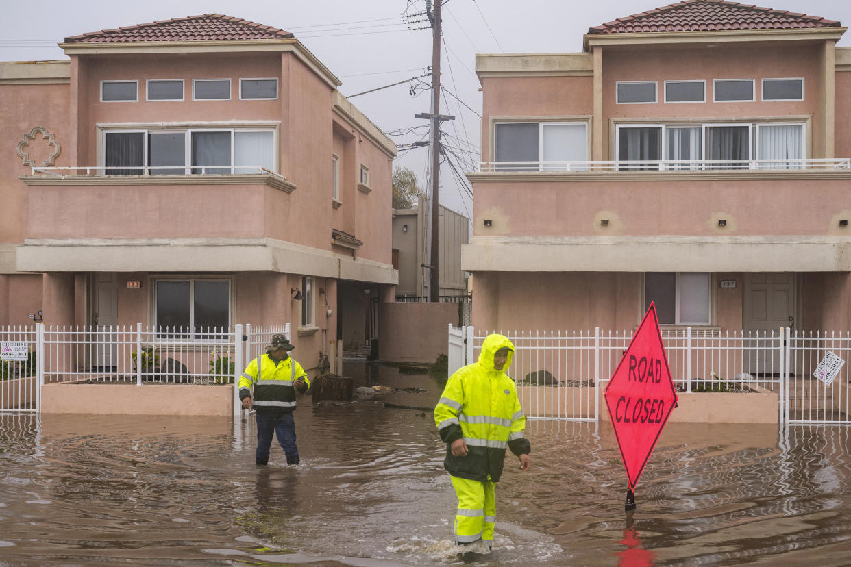 A cleaning crew walks through floodwaters in the Rio Del Mar neighborhood of Aptos, Calif., Monday, Jan. 9, 2023. (AP Photo/Nic Coury)