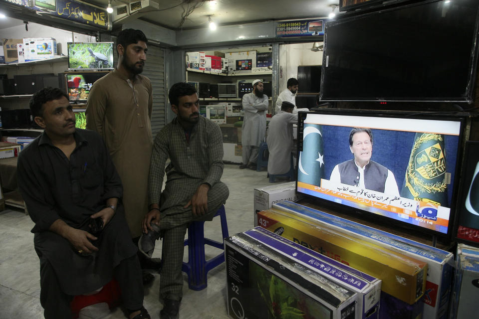 People watches news channels broadcast a live address to the nation by Pakistan's Prime Minister Imran Khan at a market, in Peshawar, Pakistan, Thursday, March 31, 2022. Pakistan's embattled Prime Minister Khan remained defiant on Thursday, telling the nation that he will not resign even as he faces a no-confidence vote in parliament and the country's opposition says it has the numbers to push him out. (AP Photo/Muhammad Sajjad)