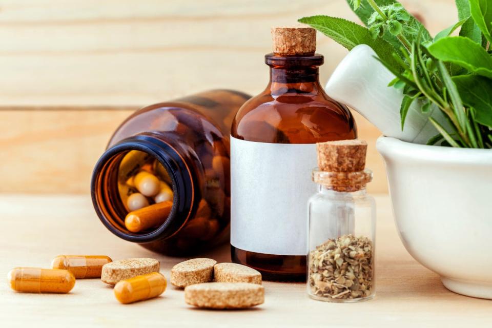 Herbs and bottles of pills sit on a table