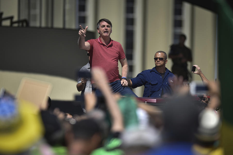 Brazil's President Jair Bolsonaro speaks to supporters during a protest in front the army's headquarters during the Army day, amid the new coronavirus pandemic, in Brasilia, Brazil, Sunday, April 19, 2020. Bolsonaro came out in support of a small protest Sunday that defended military intervention, infringing his own ministry's recommendations to maintain social distancing and prompting fierce critics. (AP Photo/Andre Borges)