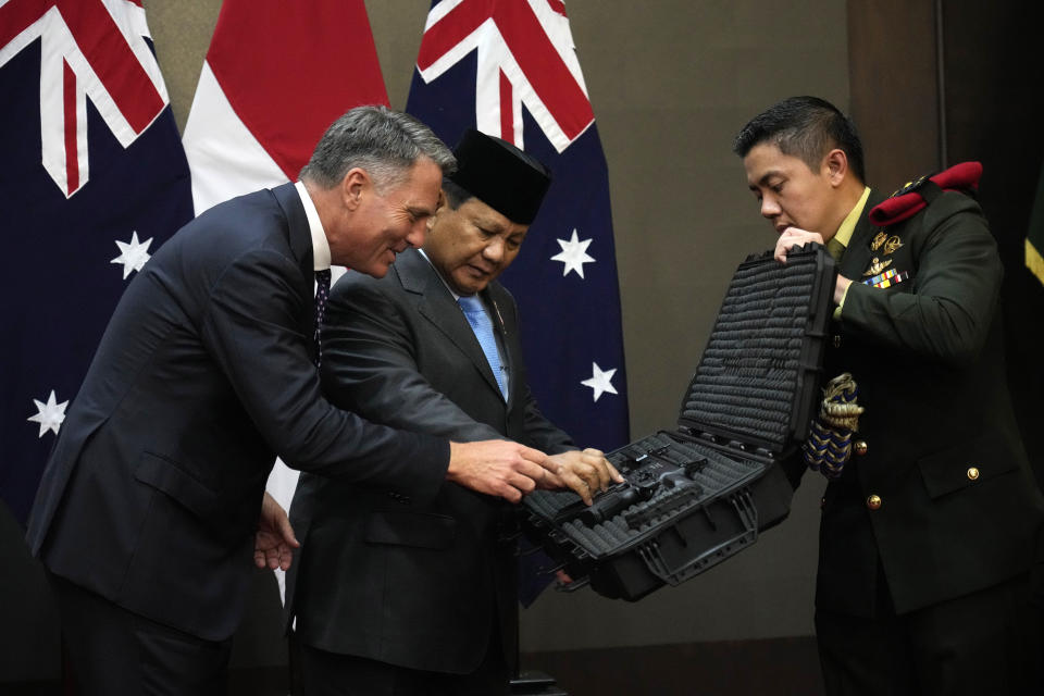 Indonesian Defense Minister Prabowo Subianto, center, gives souvenirs to Australian Deputy Prime Minister and Defense Minister Richard Marles during their meeting in Jakarta, Indonesia, Friday, Feb. 23, 2024. (AP Photo/Achmad Ibrahim)