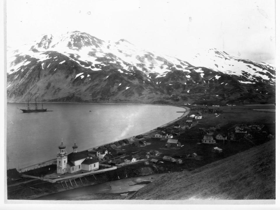 The town of Unalaska, on Unalaska Island, in the last years of the 19th Century. The town was founded in 1700s as the first headquarters of the Russian-American Company in Alaska. A Russian Orthodox church bears witness to this in the lower left.