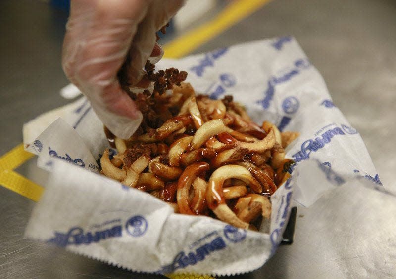 Jeremy Hogan | Herald-TimesLEFT: Chris McClellan makes loaded fries at BuffaLouie’s. RIGHT: Quincy Adams completes an order of boneless wings at BuffaLouie’s.