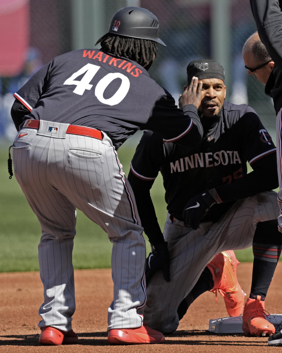 Minnesota Twins' Byron Buxton, right, is tended to by Tommy Watkins (40) after sliding into second after hitting a double during the first inning of a baseball game against the Kansas City Royals Saturday, April 1, 2023, in Kansas City, Mo. (AP Photo/Charlie Riedel)