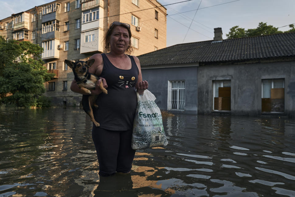 A local resident walks along a flooded street in Kherson, Ukraine, Tuesday, June 6, 2023. The wall of a major dam in a part of southern Ukraine has collapsed, triggering floods, endangering Europe's largest nuclear power plant and threatening drinking water supplies. (AP Photo/Libkos)