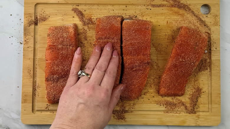 hand touching raw salmon