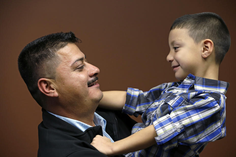 FILE - In this Oct. 17, 2014, file photo, Ignacio Lanuza holds his son, Isaiah, 4, as he has his photo taken in Seattle. A federal judge on Tuesday, Oct. 29, 2019, criticized the Justice Department for seeking legal fees from Lanuza, a Mexican immigrant who was the victim of a forgery by a government lawyer. (AP Photo/Elaine Thompson, File)