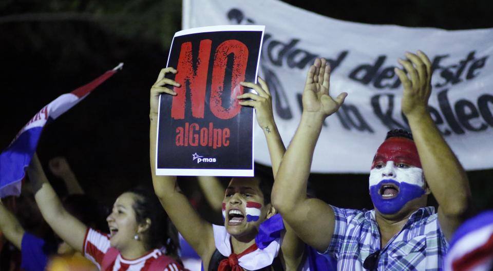 A demonstrator holds a sign that reads in Spanish " No to the coup" during a protest against the project to change the country's constitution, in Asuncion, Paraguay, Thursday, March 30, 2017. The country's upper house of Congress is split over a proposal to amend the constitution and allow for the re-election of former presidents. (AP Photo/Jorge Saenz)