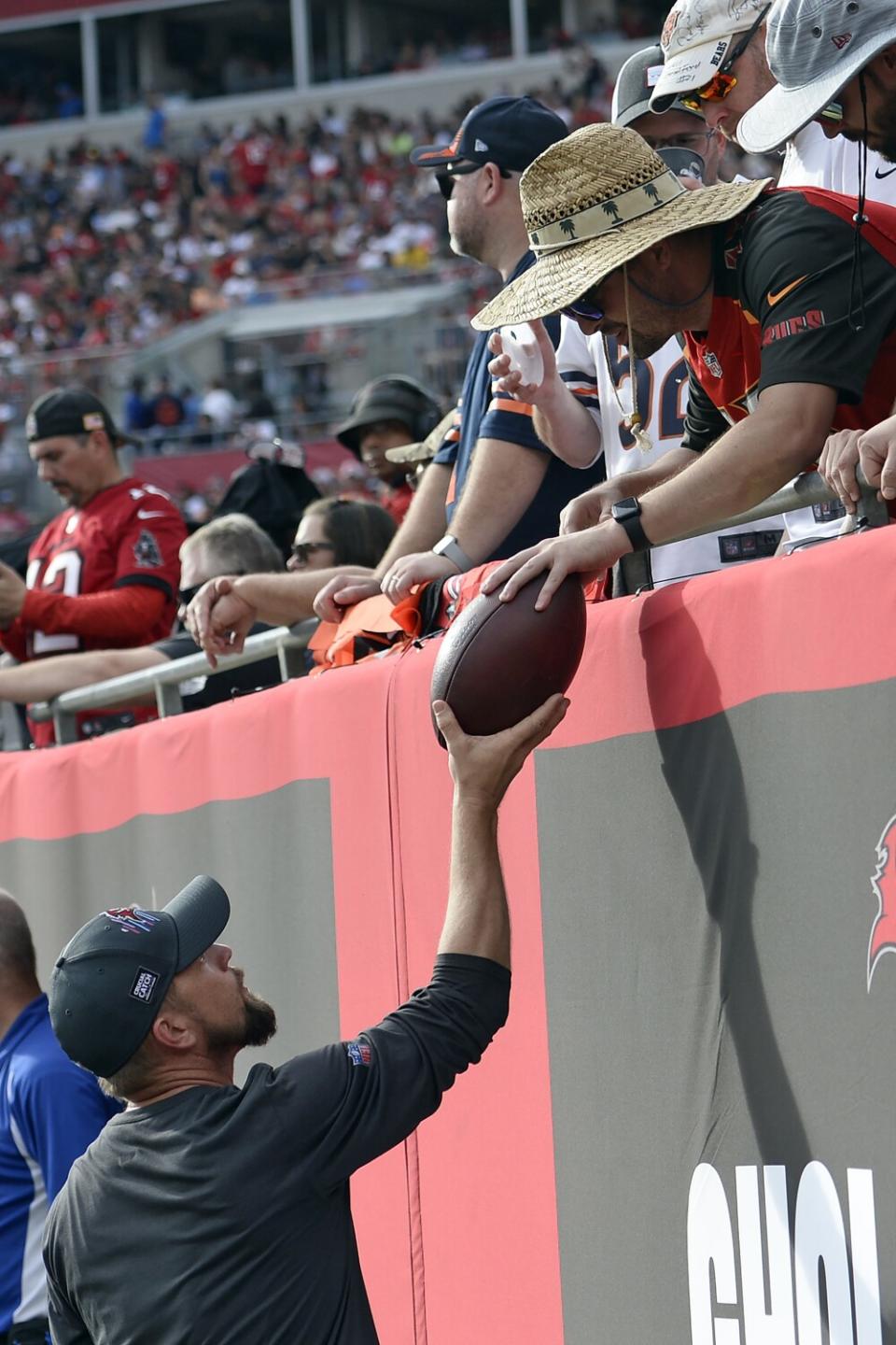 Buccaneers fan Byron Kennedy, right, hands over the milestone ball to a team official.