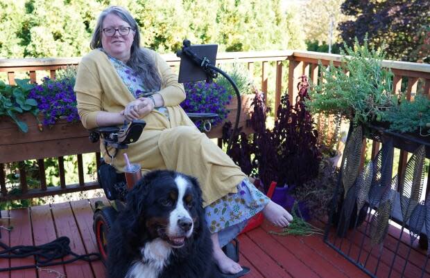 Michelle Hewitt is the co-chair of the organization Disability Without Poverty. The former public school math and music teacher and principal was diagnosed with multiple sclerosis in her early 40s. Her dog's name is Deefer. (Joseph Otoo/CBC News - image credit)