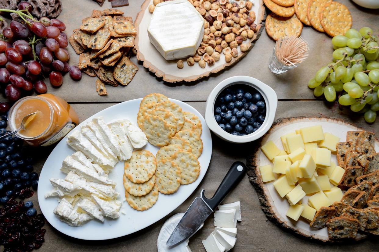 Cheese and cracker platters on three plates with blueberries in a white bowl