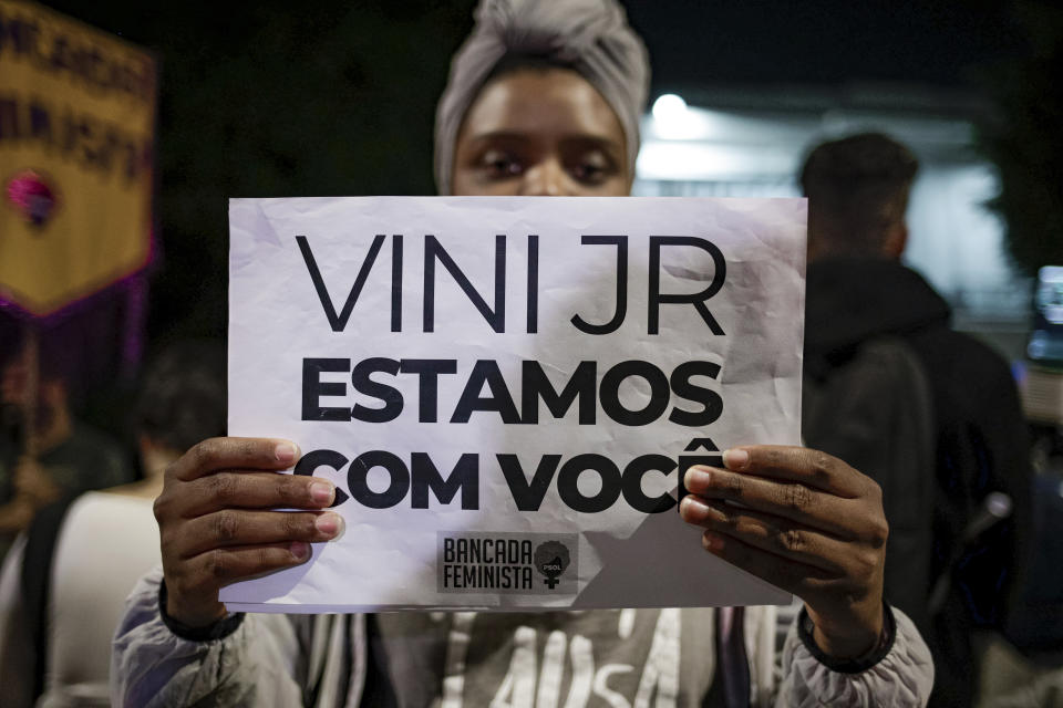 A woman holds a sign with a message that reads in Portuguese; "Vini, we are with you," during a protest against the racism suffered by Brazilian soccer star Vinicius Junior who plays for Spain's Real Madrid, outside the Spanish Consulate in Sao Paulo, Brazil, Tuesday, May 23, 2023. Vinicius, who is Black, has been subjected to repeated racist taunts since he arrived in Spain five years ago. (AP Photo/Tuane Fernandes)