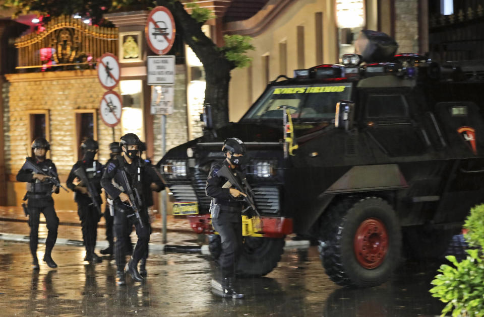 Police officers walk past an armored vehicle at the National Police Headquarters following a suspected militant attack in Jakarta, Indonesia, Wednesday, March 31, 2021. A woman entered the Indonesian National Police Headquarters in Jakarta and pointed a gun at several officers before being shot dead by police, in the latest in a series of militant attacks in the world's most populous Muslim nation. (AP Photo/Dita Alangkara)