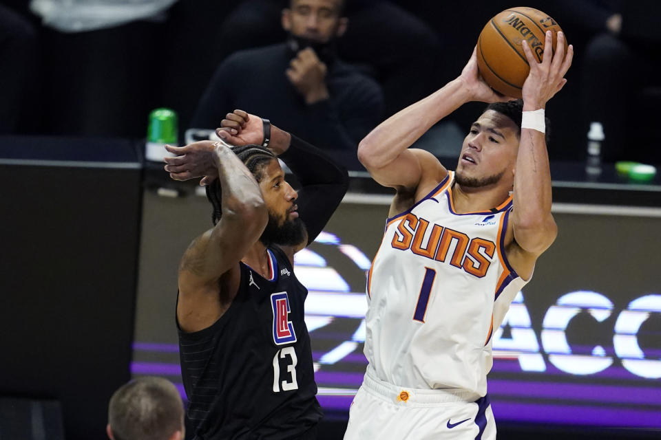Phoenix Suns guard Devin Booker (1) shoots over Los Angeles Clippers guard Paul George (13) during the first half of an NBA basketball game Thursday, April 8, 2021, in Los Angeles. (AP Photo/Marcio Jose Sanchez)