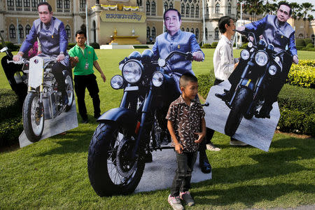 A boy stands next to cardboard cutouts of Thailand's Prime Minister Prayuth Chan-ocha during preparations for national Children's Day at the Government House in Bangkok, Thailand, January 12, 2018. REUTERS/Athit Perawongmetha