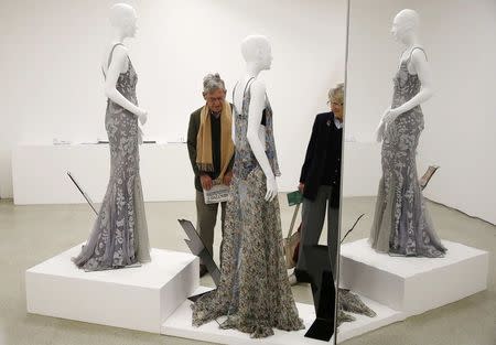 Visitors look at dresses made by Dolce & Gabbana (L) and Stella McCartney on display in the "Women Fashion Power exhibition at the Design Museum in London November 4, 2014. REUTERS/Suzanne Plunkett