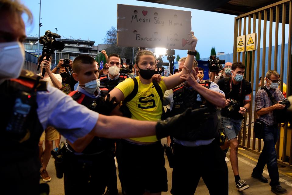 An FC Barcelona fan is escorted out of the Camp Nou stadium premises in Barcelona on August 26, 2020 as fans gather after Barcelona's Argentinian forward Lionel Messi announced his desire to leave the club. - Lionel Messi's bombshell request to leave Barcelona is expected to spark a legal battle over a multi-million-dollar buy-out clause but also raises the question of which club could afford him in the heat of the coronavirus pandemic. (Photo by Pau BARRENA / AFP) (Photo by PAU BARRENA/AFP via Getty Images)