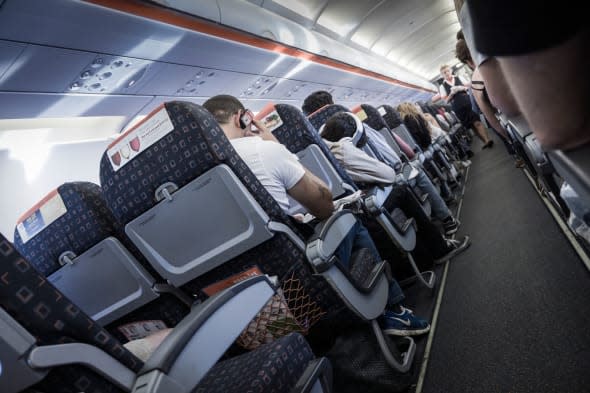 Onboard an EasyJet flight, bound for Spain, showing the flight attendant walking the aisle.