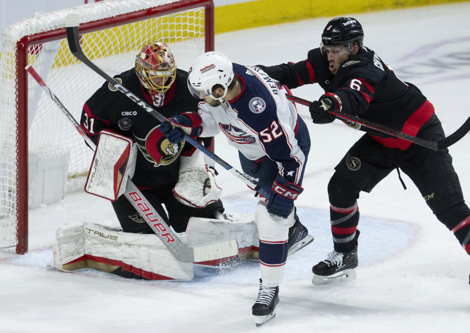 Ottawa Senators defenseman Jakob Chychrun, right, shoves Columbus Blue Jackets right wing Emil Bemstrom as he tries to deflect a shot past goaltender Anton Forsberg during the second period of an NHL hockey game, Tuesday, Feb. 13, 2024, in Ottawa, Ontario. (Adrian Wyld/The Canadian Press via AP)