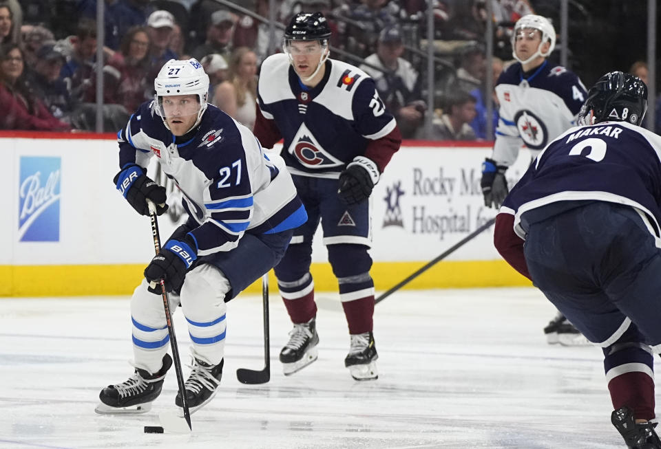 Winnipeg Jets left wing Nikolaj Ehlers, left, drives downice with the puck past Colorado Avalanche left wing Jonathan Drouin, center, and defenseman Cale Makar, front right, in the second period of an NHL hockey game Saturday, April 13, 2024, in Denver. (AP Photo/David Zalubowski)