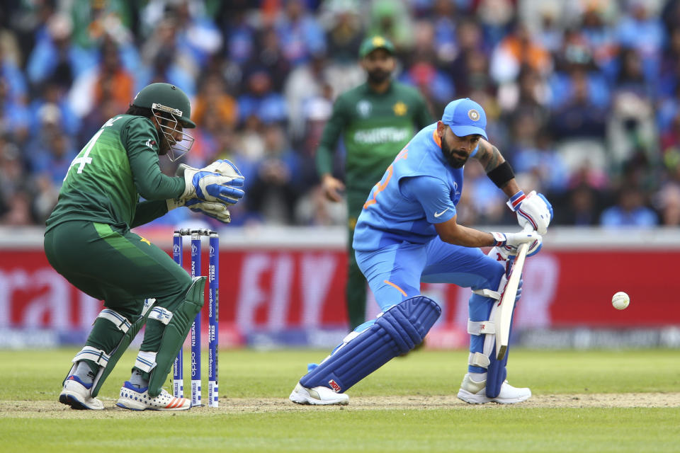 India's captain Virat Kohli, right, plays a shot under the watch of Pakistan's captain Sarfaraz Ahmed during the Cricket World Cup match between India and Pakistan at Old Trafford in Manchester, England, Sunday, June 16, 2019. (AP Photo/Dave Thompson)