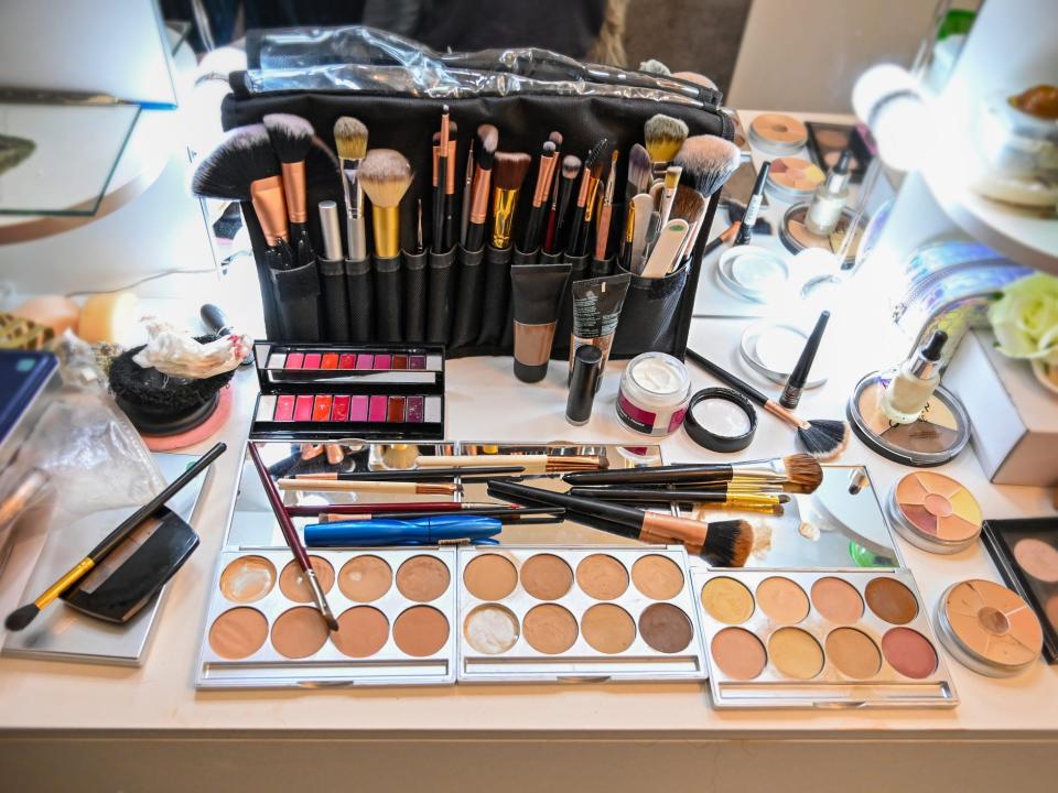 A professional makeup kit with brushes and makeup palettes on a table.