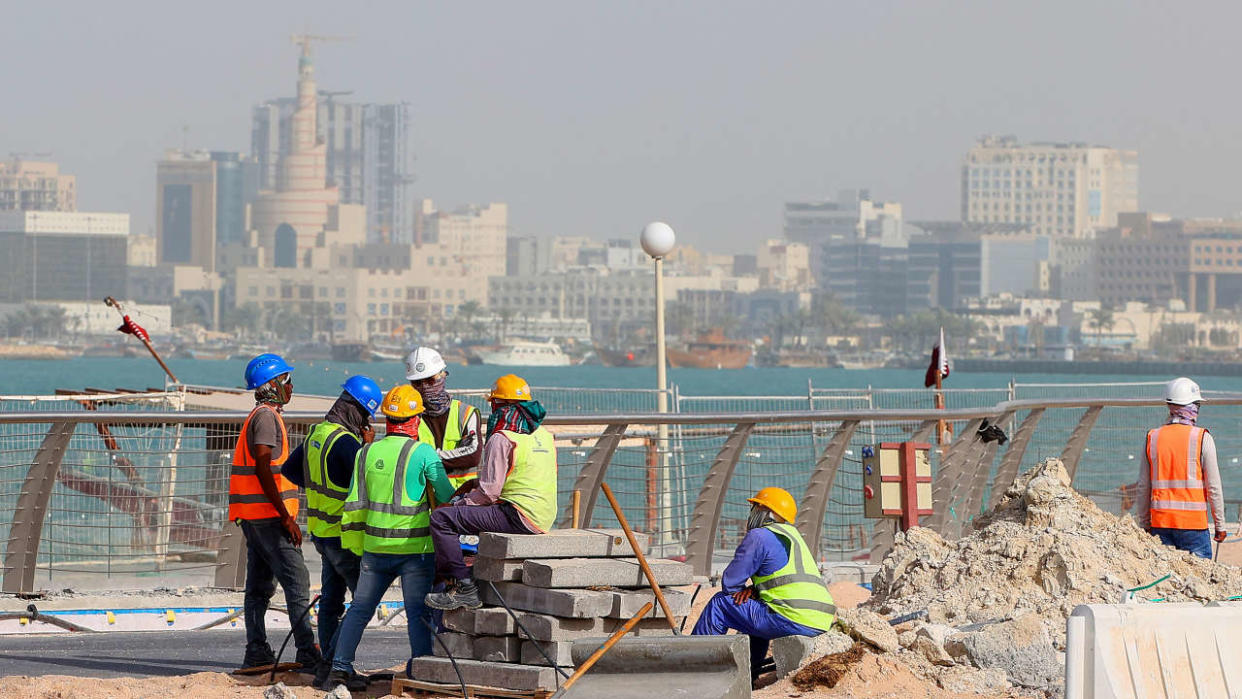 (FILES) This file photo taken on May 21, 2022 shows workers fixing a sidewalk in the capital Doha, ahead of the Qatar 2022 FIFA World Cup. - Fifty days before the World Cup kicks off in Qatar, workers are pouring concrete and hammering through the night to ready luxury hotels and bargain apartments for a million or more football fans. (Photo by KARIM JAAFAR / AFP)