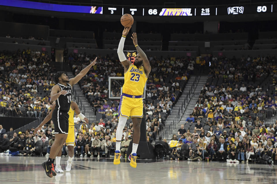 El alero de los Lakers de Los Ángeles LeBron James lanza un triple sobre el base de los Nets de Brooklyn Cam Thomas durante el encuentro de pretemporada del lunes 9 de octubre del 2023. (AP Foto/Sam Morris)