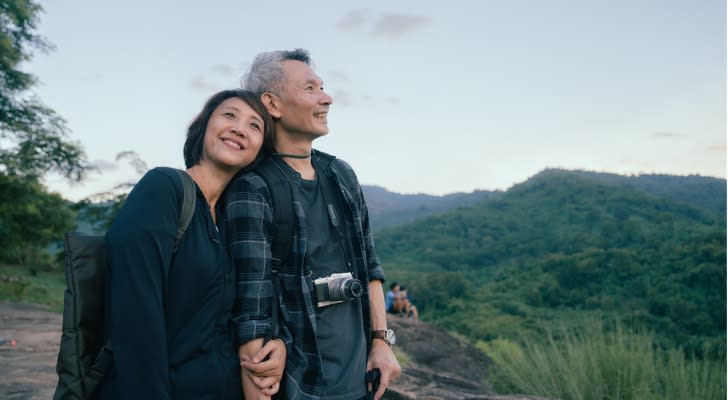 A couple enjoys the view while hiking on a vacation that is paid partially with income from their fixed annuity. 