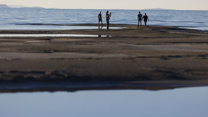 Kevin Sullivan, left, watches as Martha Sullivan, center, takes a photo while Kevin Sullivan holds the hand of his girlfriend, Linnea Scott, as they walk the shore of the Great Salt Lake in Salt Lake City on Sept. 24, 2022. The Church of Jesus Christ of Latter-day Saints has agreed to reroute and donate 20,000 acre-feet of water it had used for agriculture to the help sustain the Great Salt Lake.