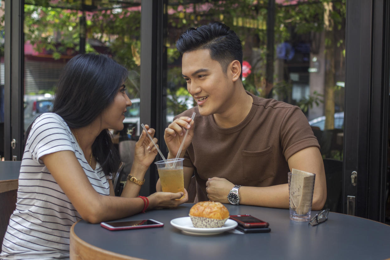 A couple in love drinking juice from the same glass outdoor on a date (Photo: Getty Images)