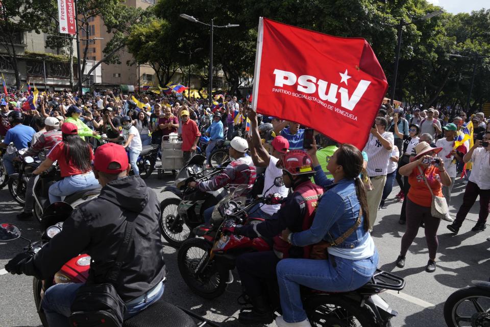 Seguidores del presidente venezolano, Nicolás Maduro, pasan al lado de simpatizantes del candidato opositor Edmundo González Urrutia para dirigirse a un acto por el inicio oficial de la campaña para las elecciones presidenciales del 28 de julio en Caracas, Venezuela, el jueves 4 de julio de 2024. (AP Foto/Ariana Cubillos)