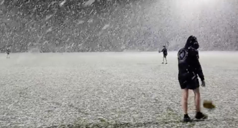 Members of the Prospect Hawks Football Club kick a football in driving snow at Gallagher Prospect Park in Launceston, Tasmania.