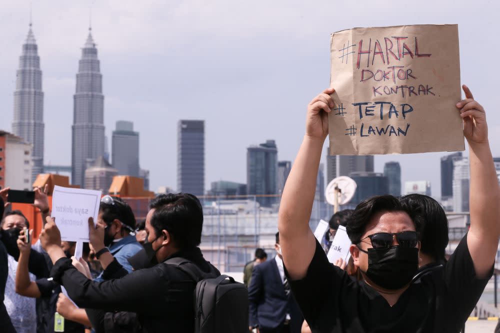 Contract doctors hold aloft placards demanding equal treatment as they go on strike at the Kuala Lumpur Hospital July 26, 2021. — Picture by Ahmad Zamzahuri