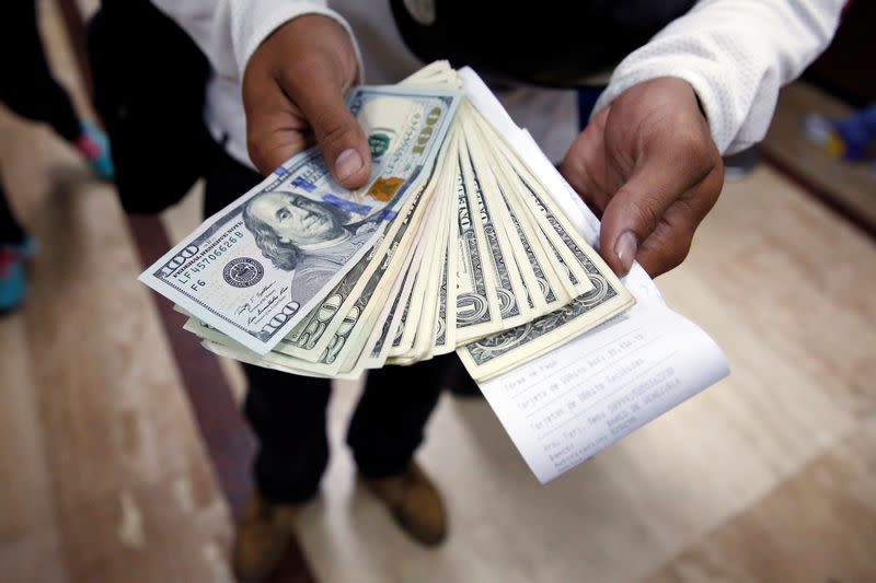 FILE PHOTO: A man poses with dollars, after buying them at a money exchange in Caracas