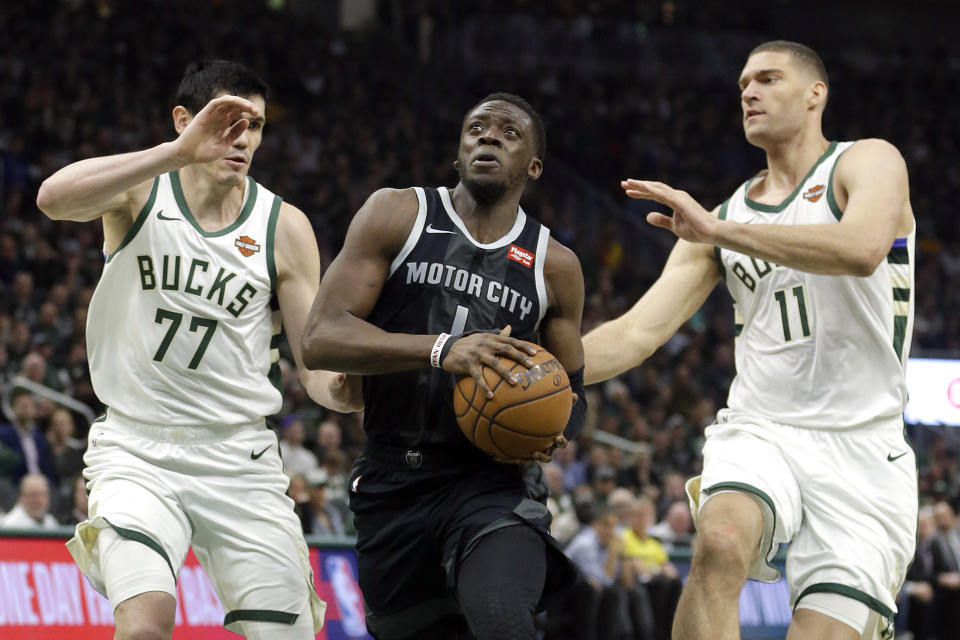 Detroit Pistons' Reggie Jackson, middle, drives between Milwaukee Bucks' Ersan Ilyasova (77) and Brook Lopez (11) during the first half of Game 2 of an NBA basketball first-round playoff series Wednesday, April 17, 2019, in Milwaukee. (AP Photo/Aaron Gash)