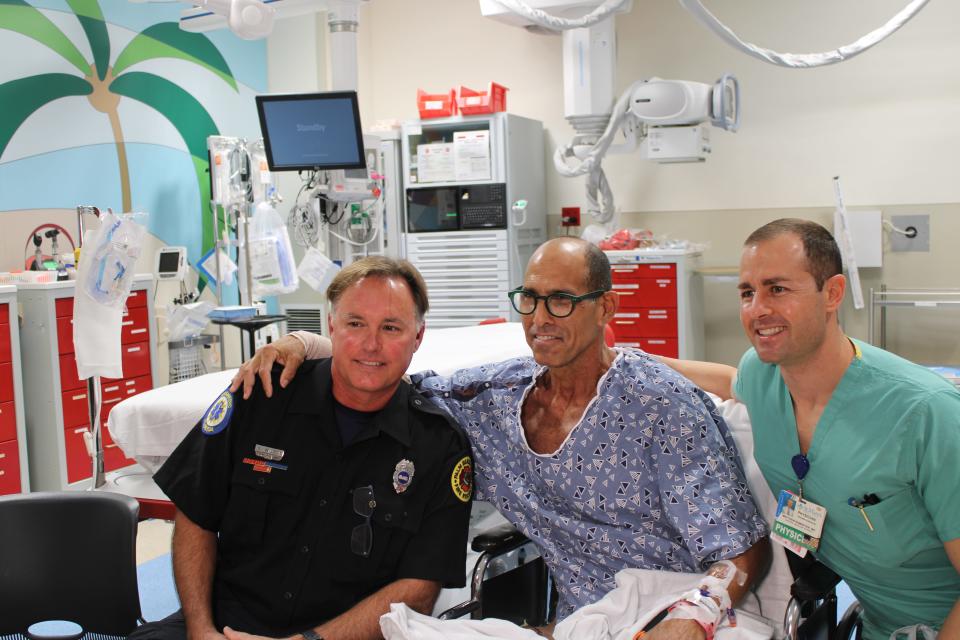Steven Reinhardt, 60, of Palm Beach Gardens huddles in with Gordon Wilson (left), the Palm Beach County paramedic who treated him, and Dr. Matthew Ramseyer (right), the doctor who performed two surgeries on his right arm, which was bit by a shark in Juno Beach on Nov. 5, 2023.