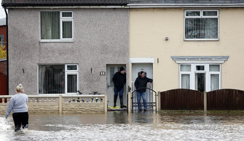 Residents stand on sandbags at their front doors in a flooded area of Bentley