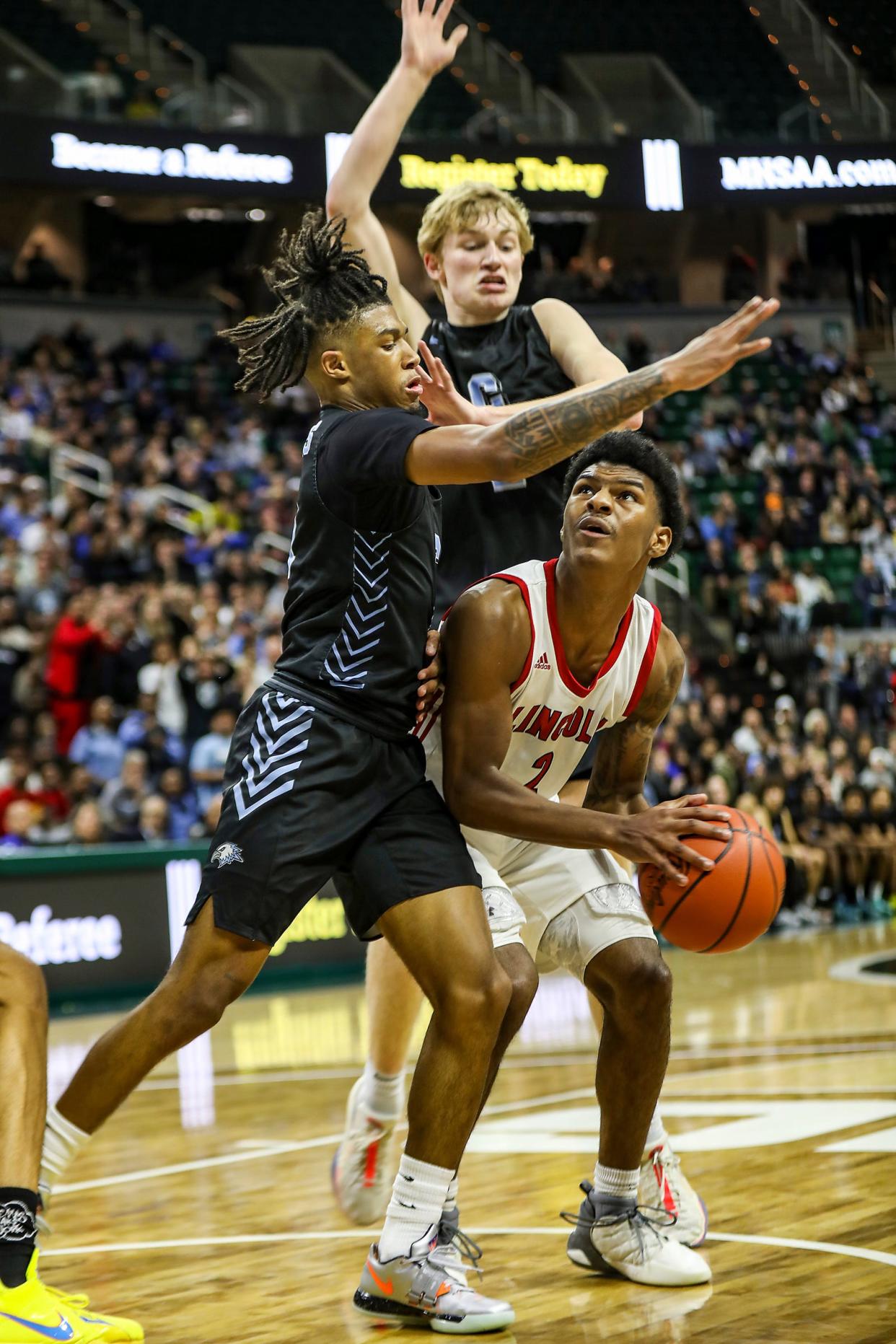 Warren Lincoln’s Markus Blackwell goes for two against Grand Rapids Christian’s Malachi Hooser and Carter Goodyke during the MHSAA boys basketball Division 2 final at Breslin Center in East Lansing on Saturday, March 16, 2024.