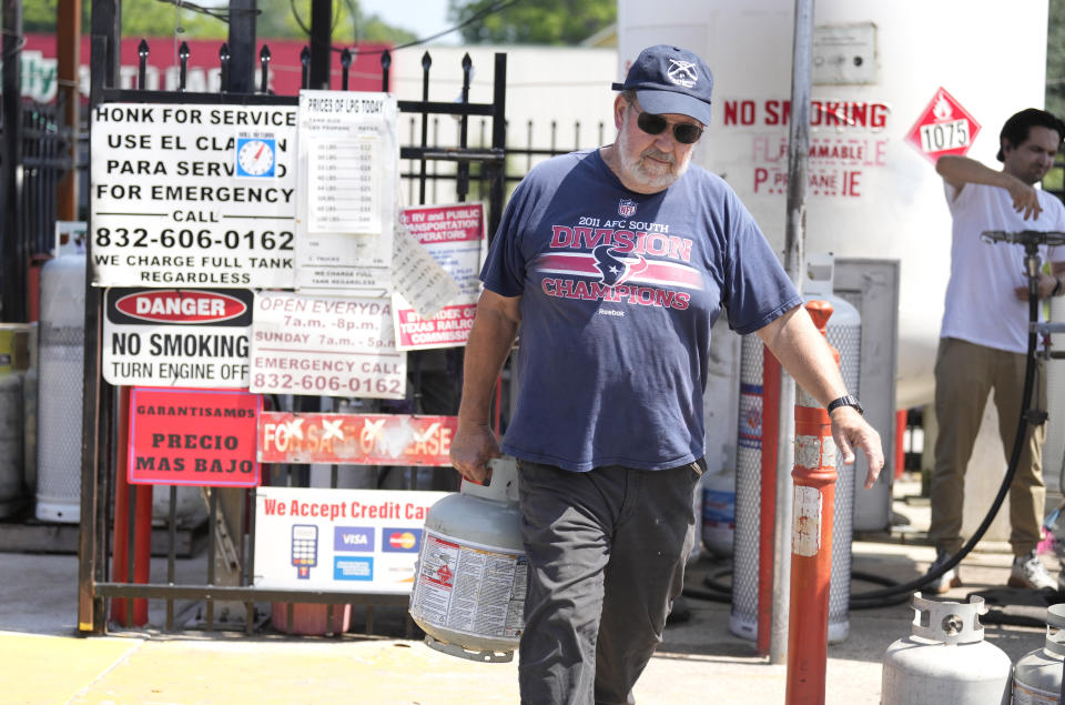 A man carries his propane tank after getting it filled up at 2650 Tidwell Road on Saturday, May 18, 2024, in Houston, after a strong thunderstorm moved through Thursday evening. (Karen Warren/Houston Chronicle via AP)