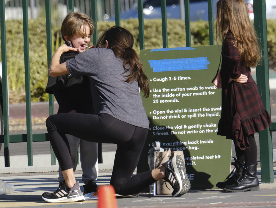 A woman swabs a child's cheek for a COVID-19 test at a testing site in the North Hollywood section of Los Angeles on Saturday, Dec. 5, 2020. With coronavirus cases surging at a record pace, California Gov. Gavin Newsom announced a new stay-at-home order and said if people don't comply the state's hospitals will be overwhelmed with infected patients.(AP Photo/Richard Vogel)