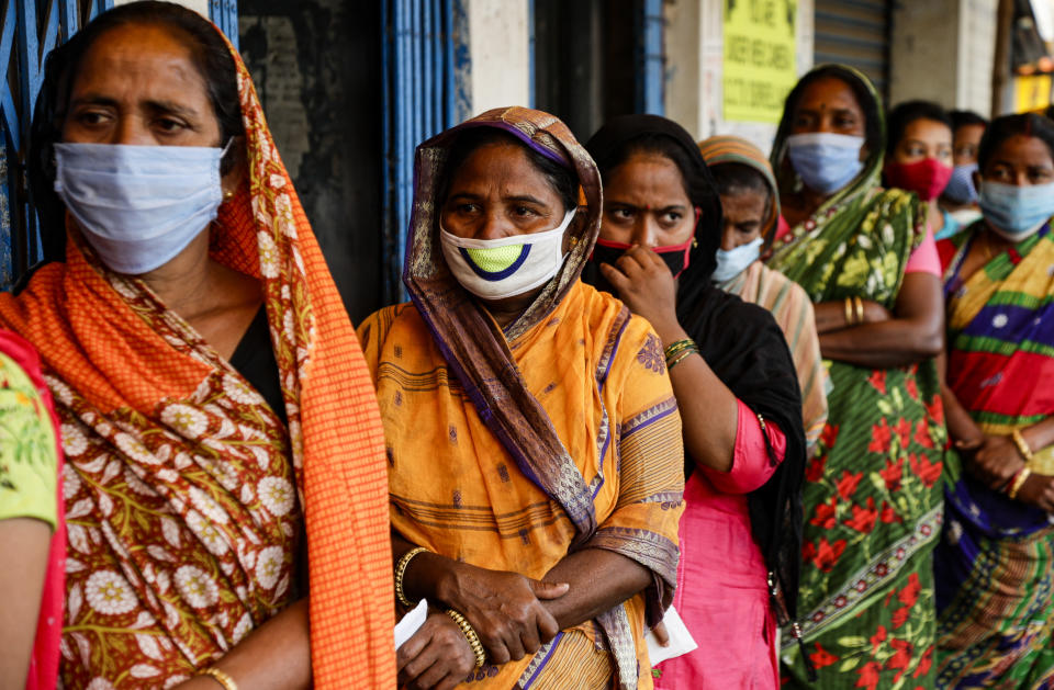 Voters stand in a queue to cast their votes outside a polling booth during first phase of elections in West Bengal state in Medinipur, India, Saturday, March 27, 2021. Voting began Saturday in two key Indian states with sizeable minority Muslim populations posing a tough test for Prime Minister Narendra Modi’s popularity amid a months-long farmers’ protest and the economy plunging with millions of people losing jobs because of the coronavirus pandemic. (AP Photo/Bikas Das)