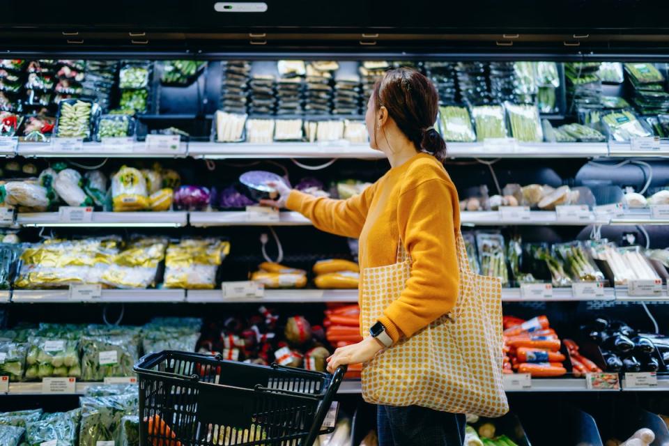 stock image of woman in grocery store picking out produce