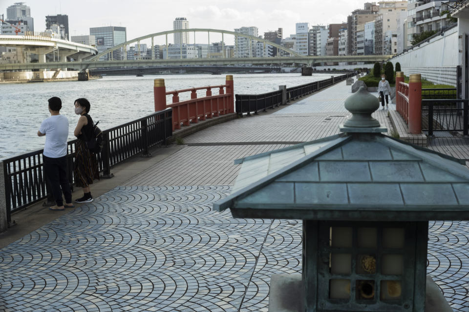 A man and a woman wearing face masks watch the Sumida River as they visit its riverside walking trail in Tokyo, Thursday, Sept. 16, 2021. (AP Photo/Hiro Komae)