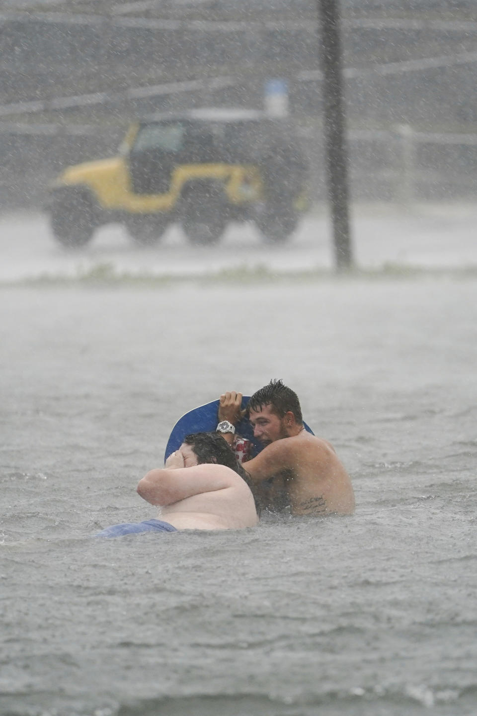 People play in a flooded parking lot at Navarre Beach, Tuesday, Sept. 15, 2020, in Pensacola Beach, Fla. Hurricane Sally is crawling toward the northern Gulf Coast at just 2 mph, a pace that's enabling the storm to gather huge amounts of water to eventually dump on land. (AP Photo/Gerald Herbert)