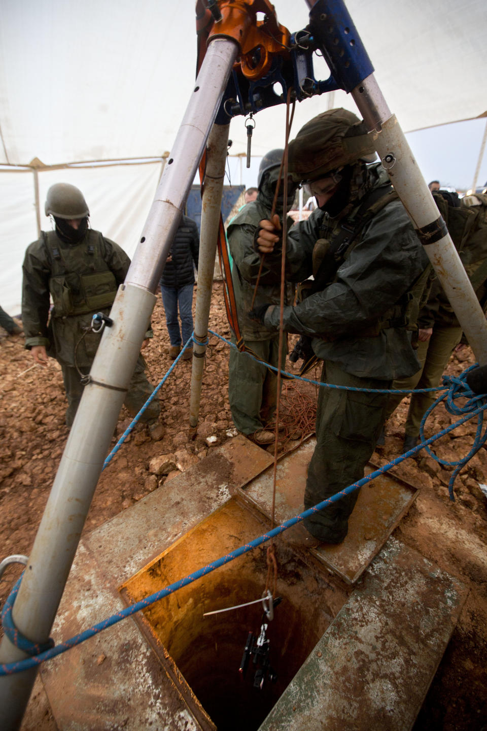 Israeli soldiers lower a tool into a hole that leads to a tunnel that the army says crosses from Lebanon to Israel, near Metula, Wednesday, Dec. 19, 2018. Israel's prime minister Wednesday called on the U.N. Security Council to condemn "wanton acts of aggression" by the Lebanese militant group Hezbollah, designate it a terrorist organization and heighten sanctions on it over attack tunnels it has dug into Israel. (AP Photo/Sebastian Scheiner)