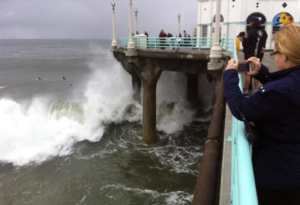 Big surf pounds the pier at Manhattan Beach, Calif., on Sunday, March 2, 2014, in the aftermath of a powerful Pacific storm. Showers from residual moisture fell in the region, but forecasters said a developing ridge of high pressure would bring a period of dry weather. (AP Photo/John Antczak)