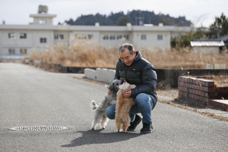 Yoichi Yatsuda plays with his dogs after moving back to his home in Futaba town of Fukushima prefecture, Japan, Thursday, Jan. 20, 2022. Several former residents of Futaba, including Yatsuda, the only remaining uninhabited town in Japan still recovering from effects of radiation from nuclear plant meltdowns in 2011, have returned to live for the first time since the massive earthquake and tsunami forced them out. (Kota Endo/Kyodo News via AP)