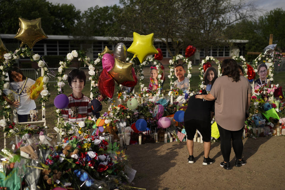 Jolean Olvedo, left, weeps while being comforted by her partner Natalia Gutierrez at a memorial for Robb Elementary School students and teachers who were killed in last week's school shooting in Uvalde, Texas, Tuesday, May 31, 2022. (AP Photo/Jae C. Hong)